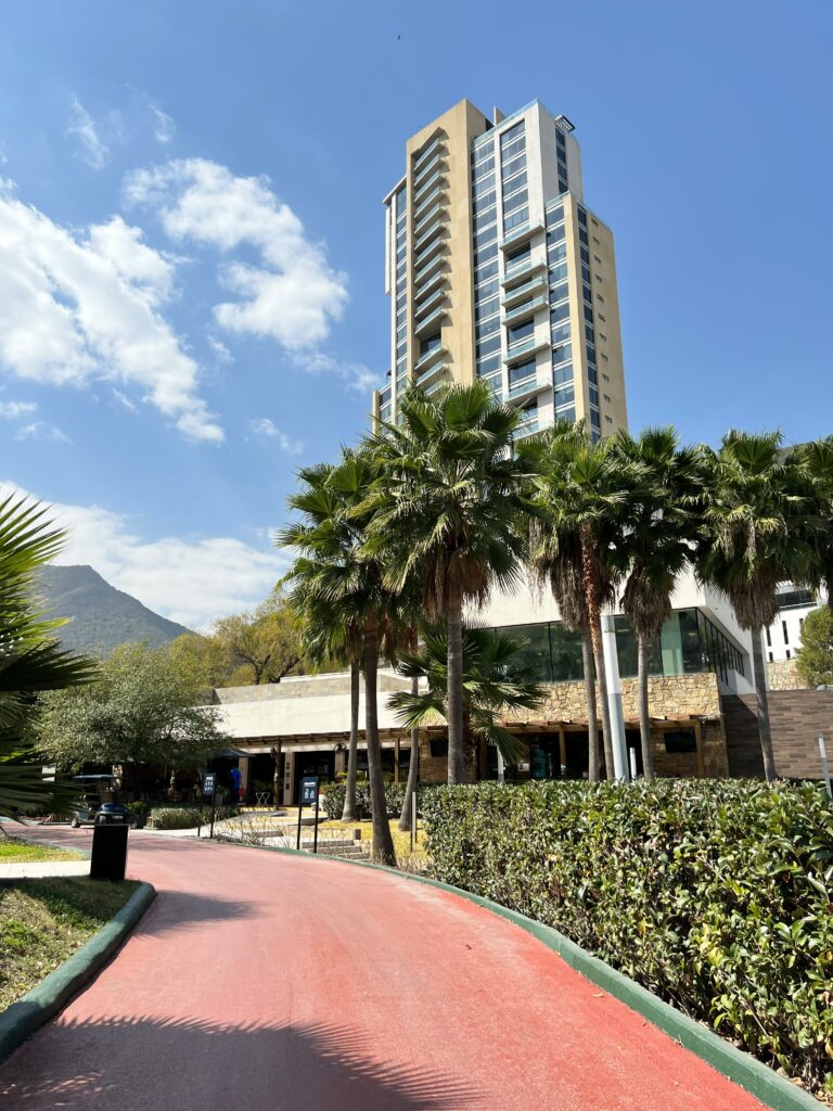 A red walkway going through the apartments building with palm trees across the walkway